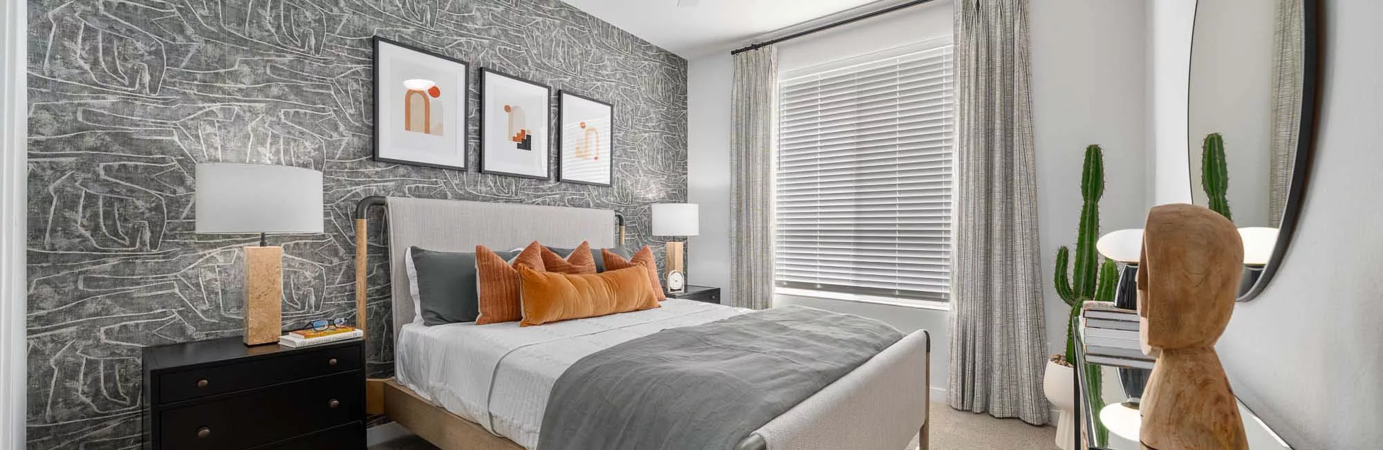 Stylish bedroom with abstract accent wall, modern decor, and large window with blinds.
