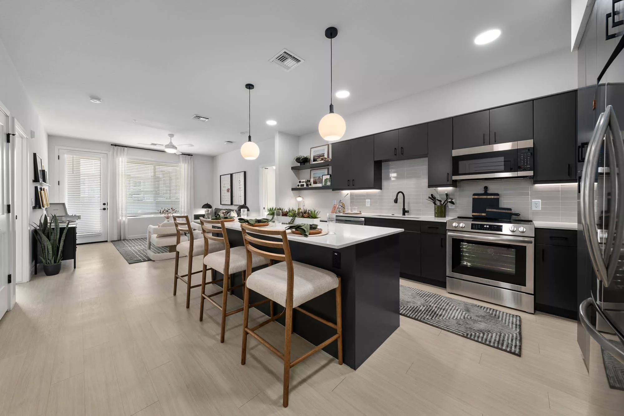 Contemporary open kitchen with black cabinets, island seating, and view into living area.